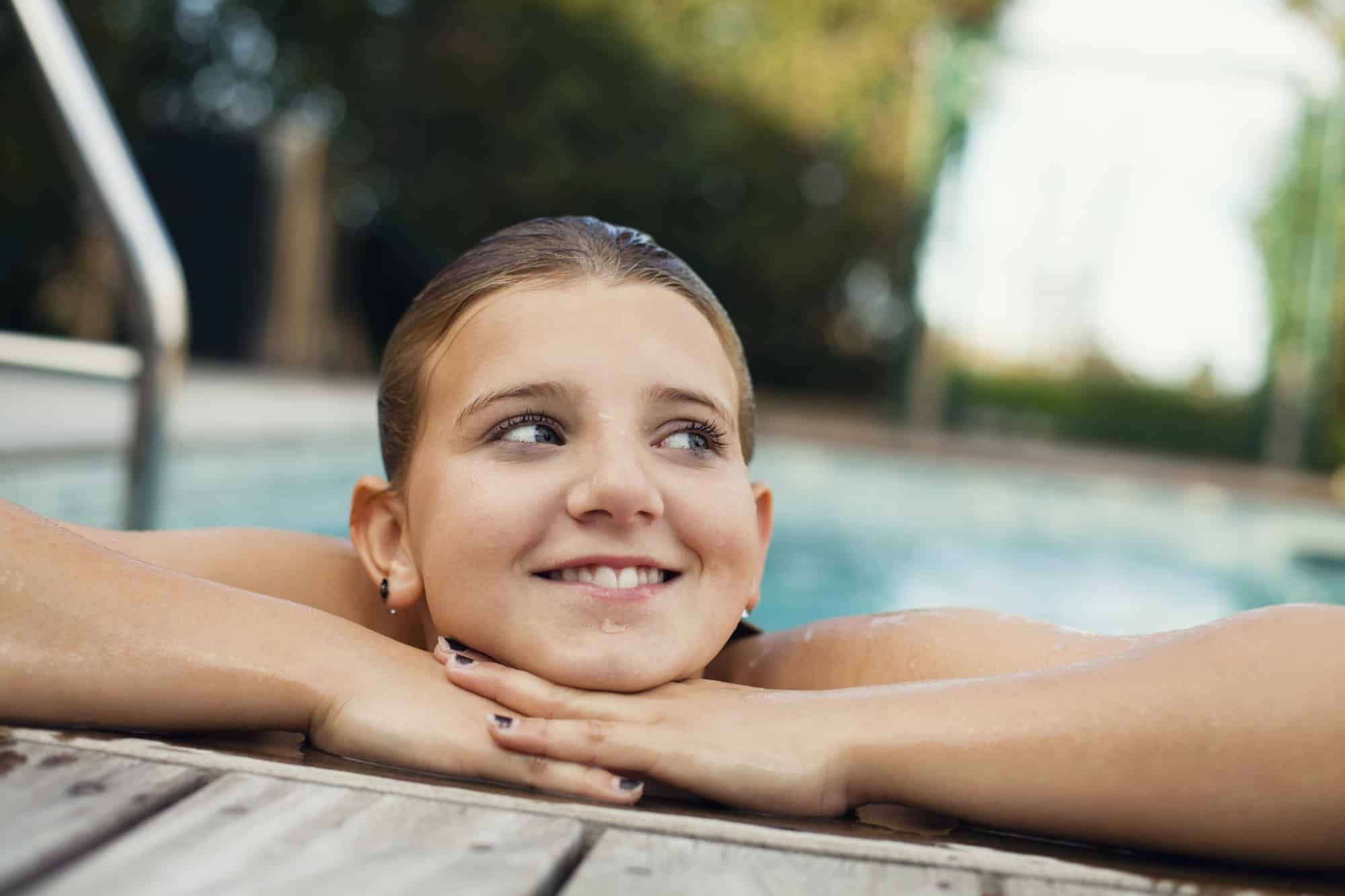 Happy girl leaning at poolside in back yard