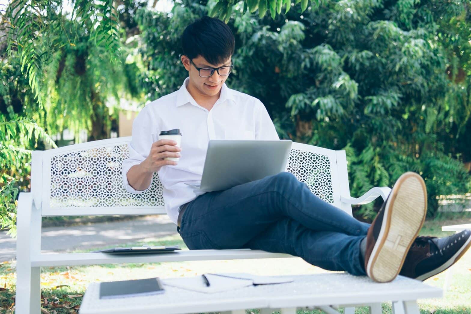 Relaxed businessman using computer laptop while sitting on a bench outdoor office