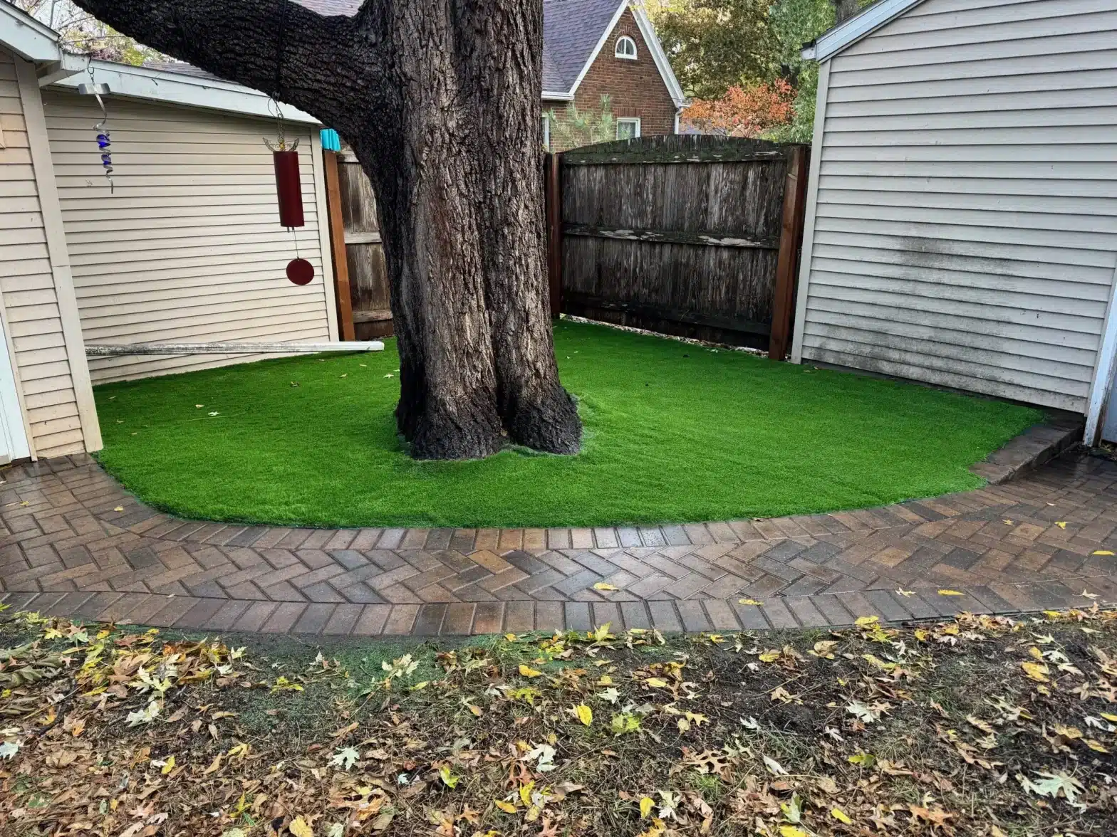 artificial turf grass around a tree in front of a home